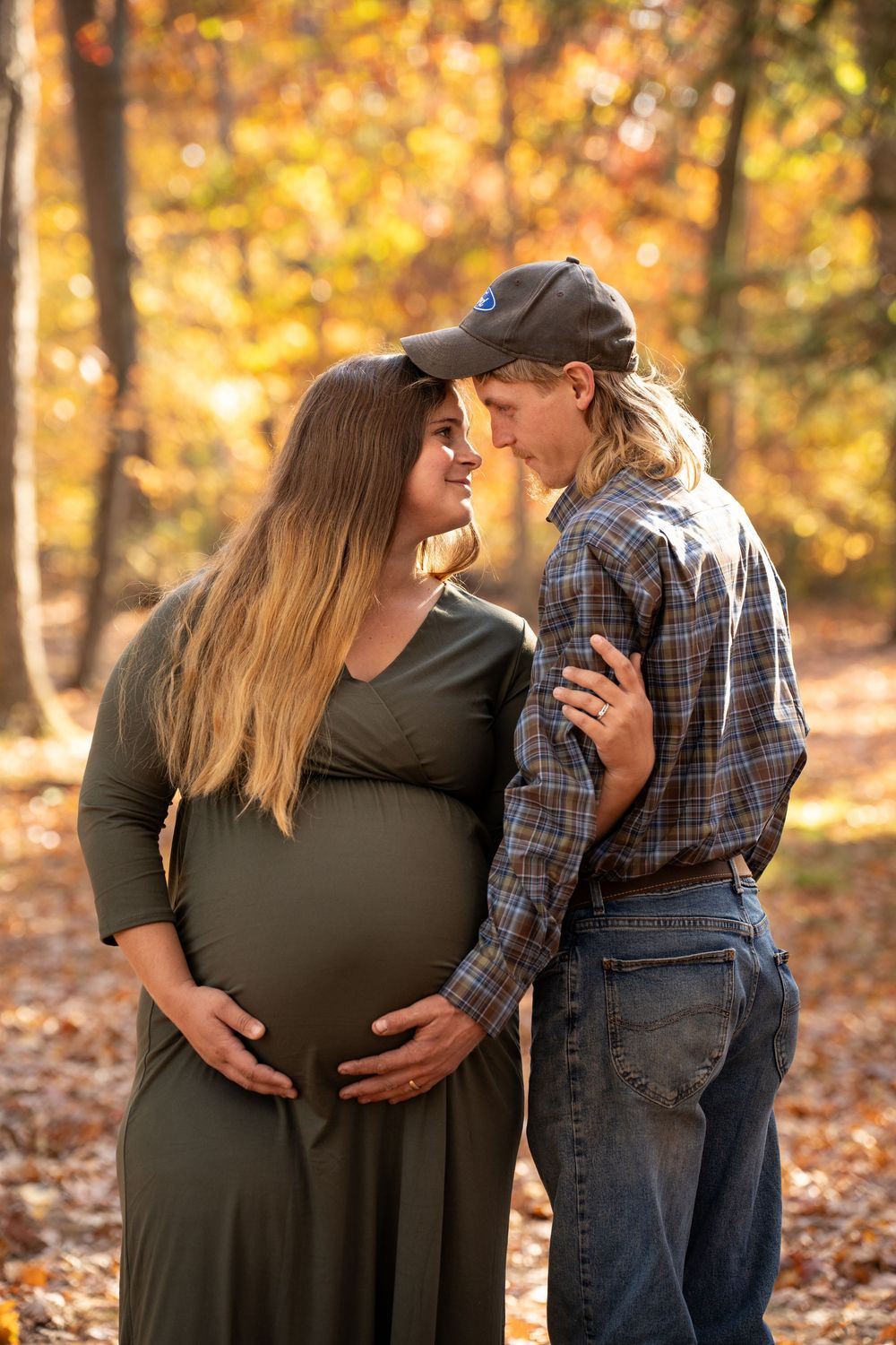 A tender moment between a couple in autumn as they embrace on fallen leaves with warm golden sunlight filtering through trees.