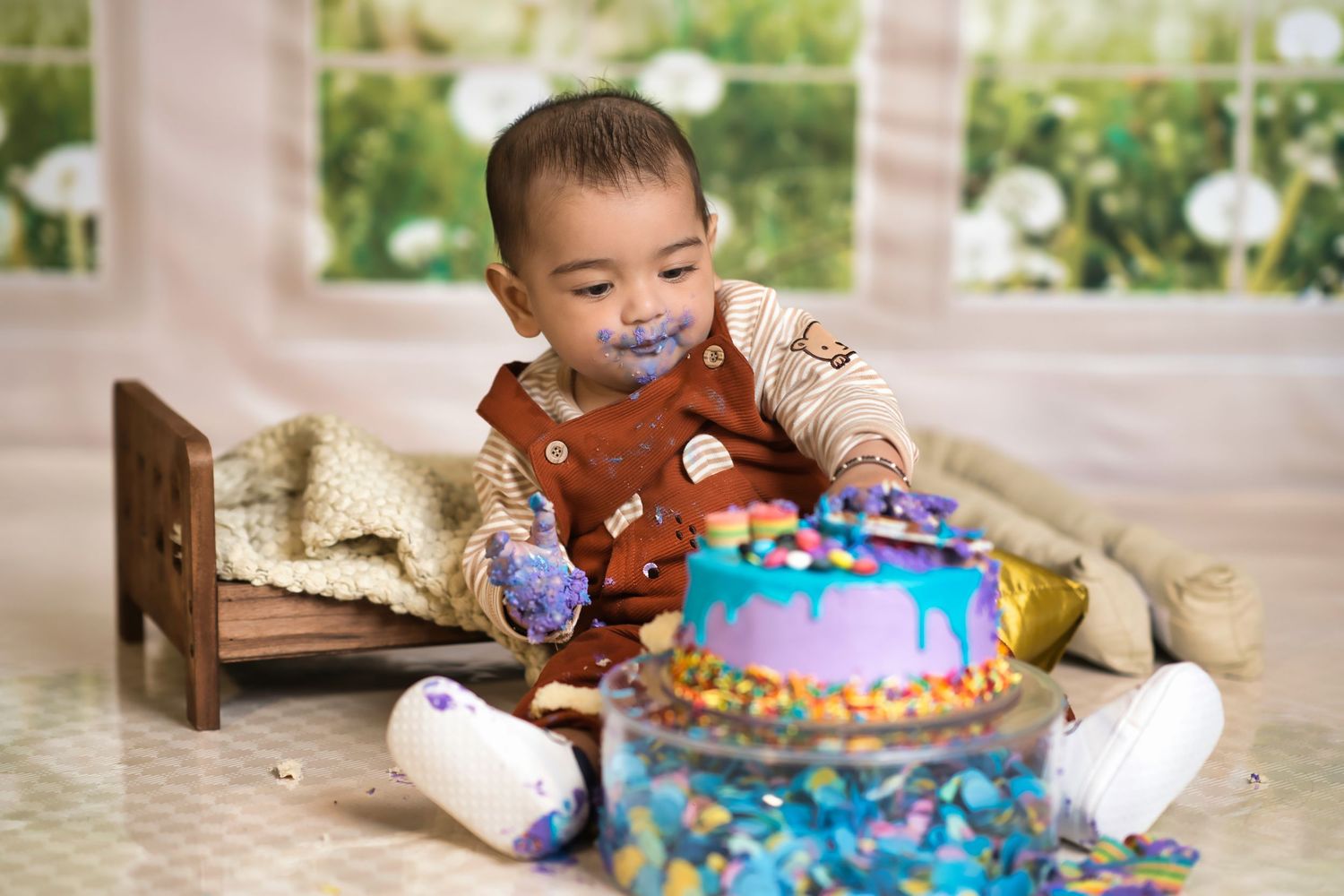 Family celebrates at a party with colorful balloon arch decorations in pastel green and purple colors in the background.