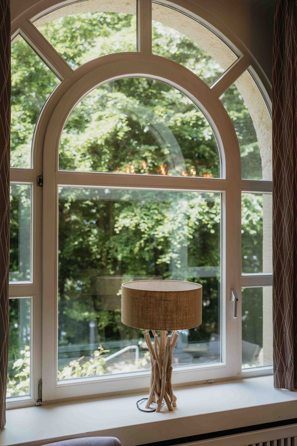 Row of elegant arched windows with natural light streaming through and decorative lamps.