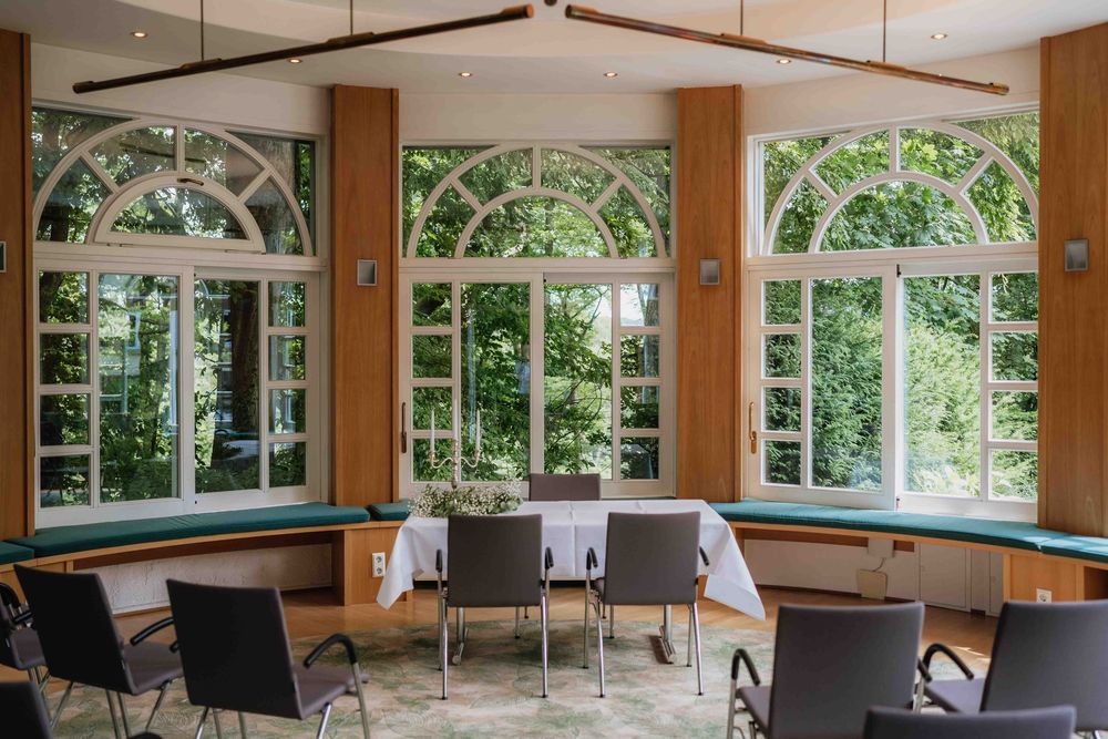Modern dining room interior with large arched windows and contemporary furniture.