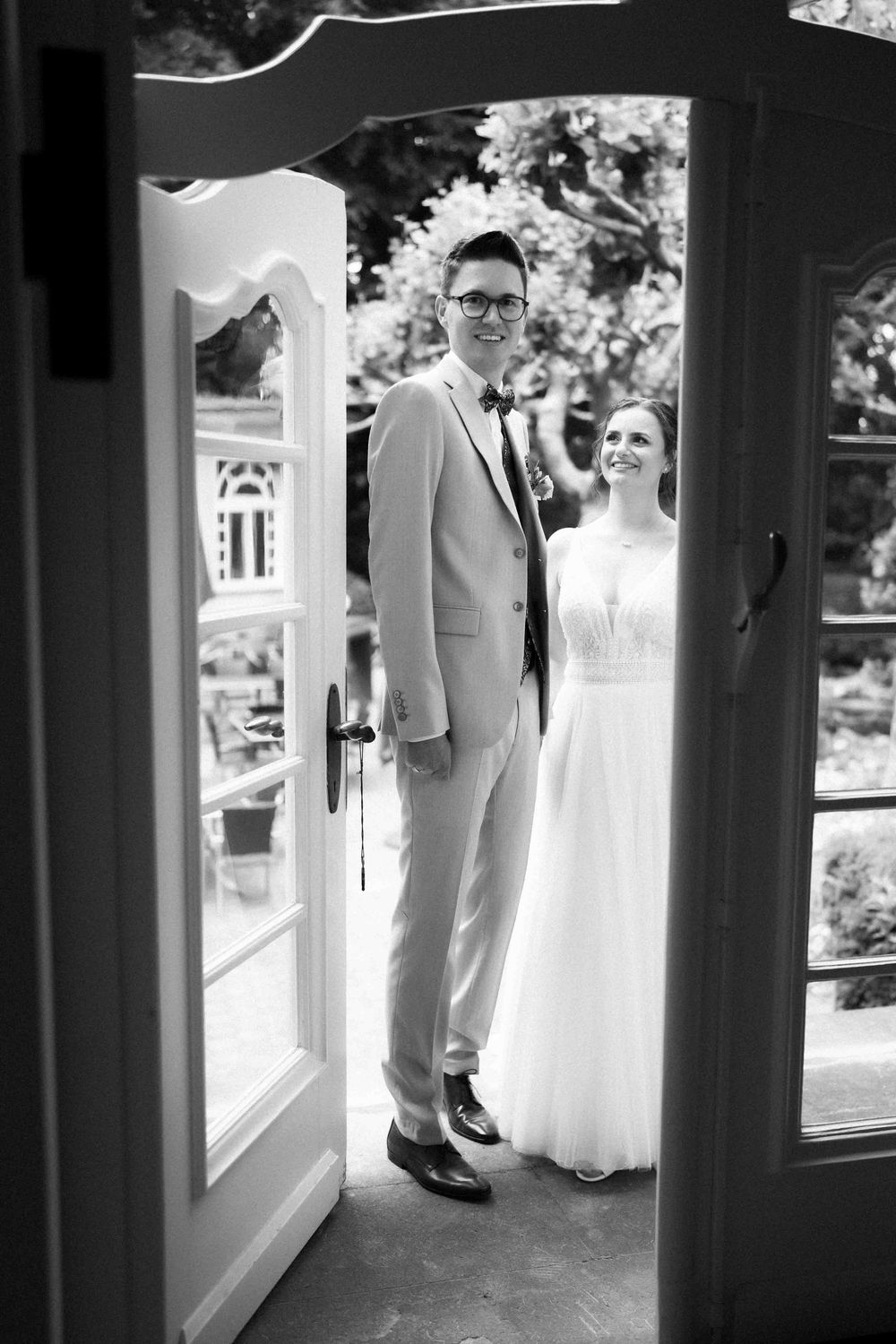Black and white photos of couple through window frames creating framed wedding portraits.