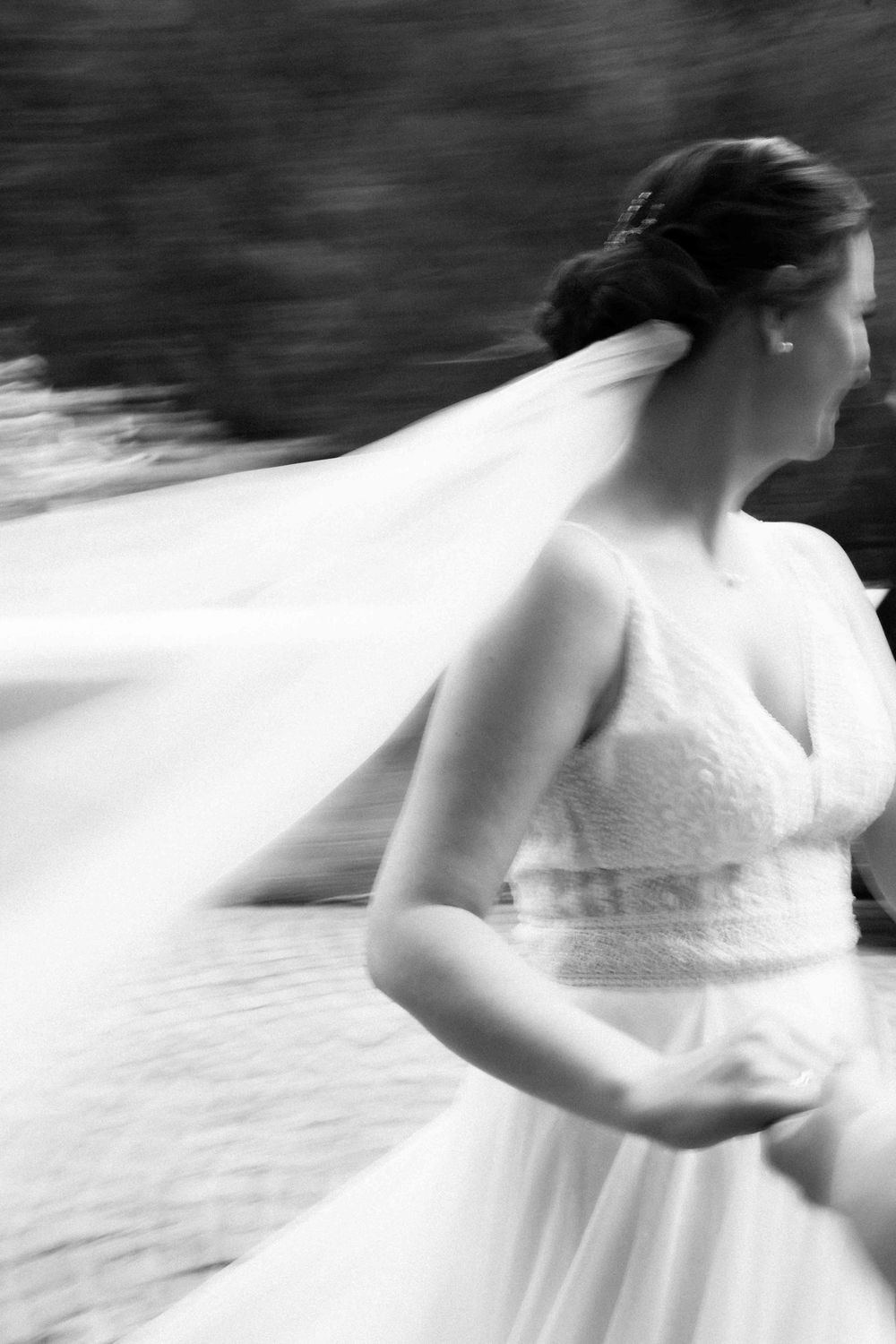 Artistic black and white motion blur of a bride's flowing dress and veil.