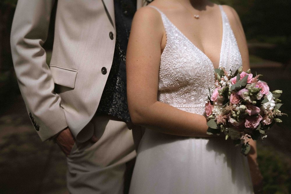 Intimate wedding portrait showing details of lace dress and light tan suit.