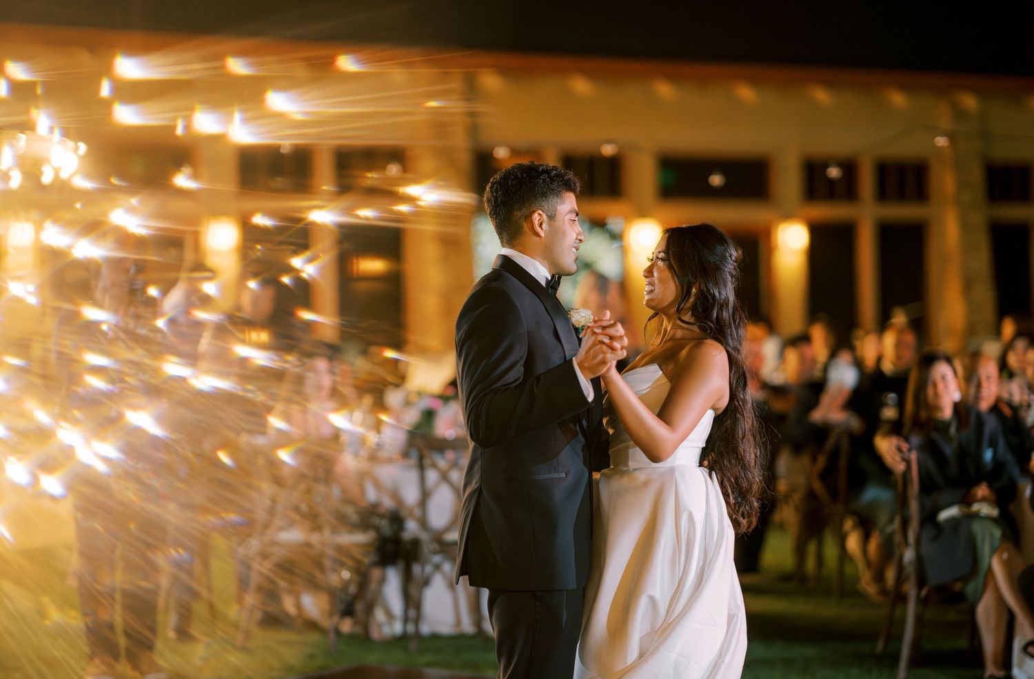 A romantic first dance moment with sparklers creating magical light trails in the background.