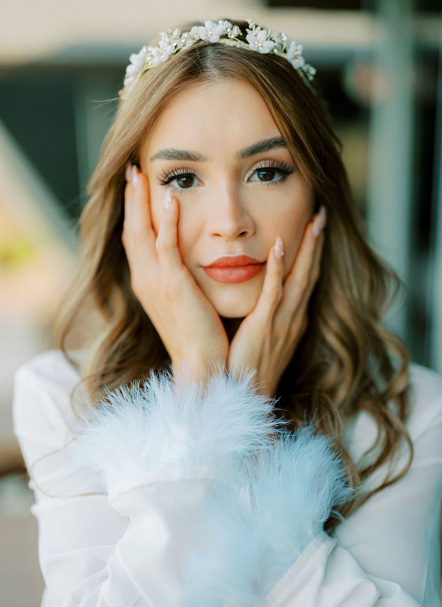 Bridal portrait with floral crown and white feather details.