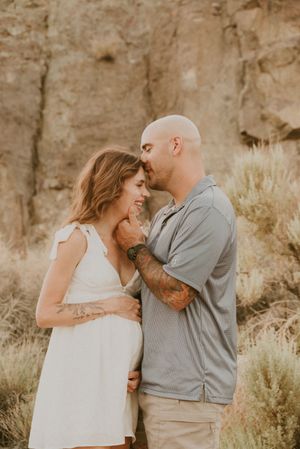 An intimate moment between a couple in white and grey attire against a desert canyon backdrop.