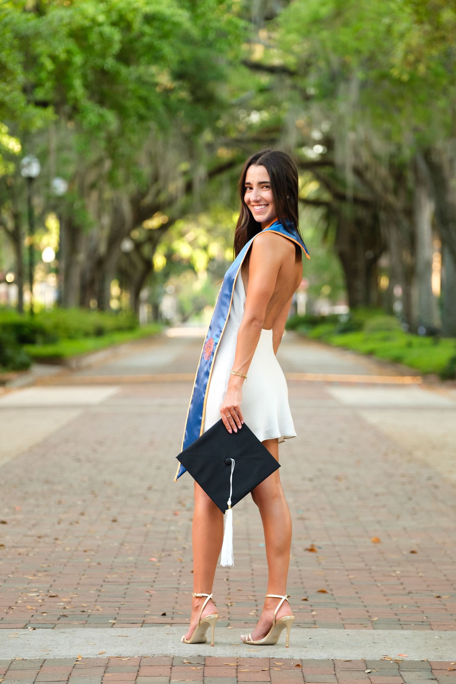 Smiling UF grad looks over her left shoulder holding her cap.