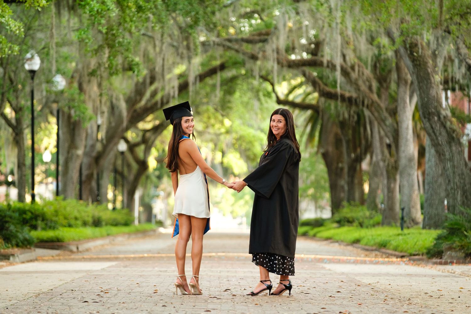 Mother and daughter look back over their should at the camera during a grad session at UF.