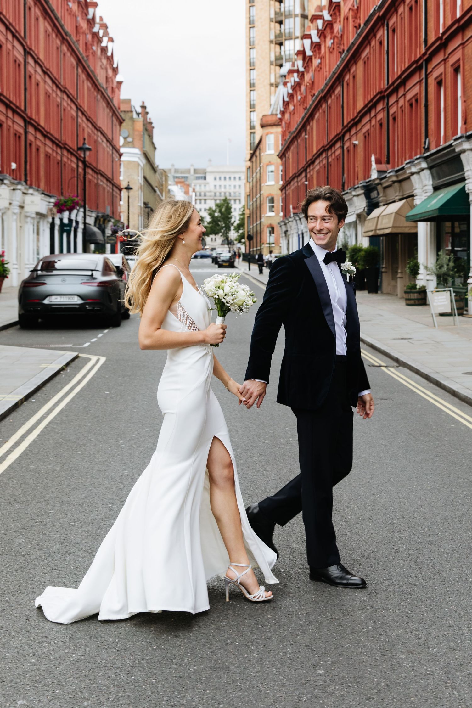 Playful black and white wedding photo sequence showing a bride and groom dancing in front of historic buildings in Edinburgh.