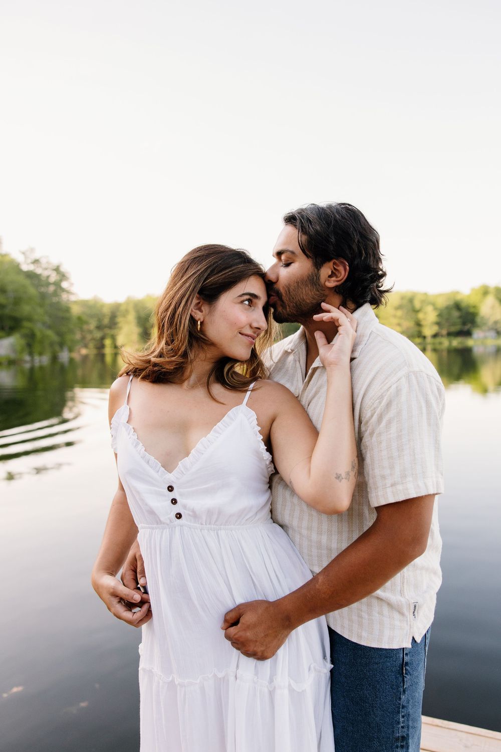 A romantic lakeside moment captured at sunset with reflections on the water.