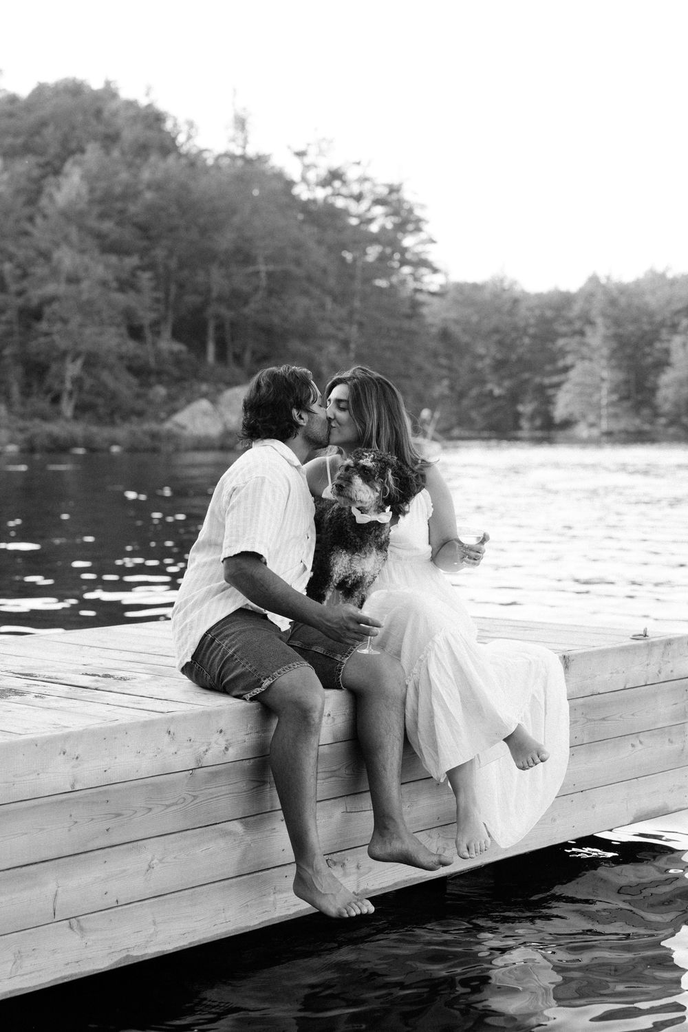 A couple sharing an intimate moment on a wooden dock by the lake in black and white.