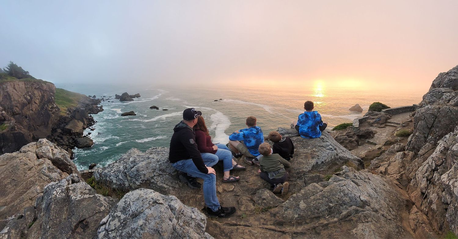 Scenic coastal sunset view with rocky cliffs and ocean waves.