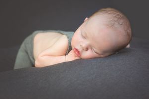 Artistic black and white series of a sleeping newborn against dark background.