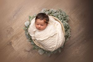 A collection of newborn photography portraits showing a sleeping baby wrapped in cream fabric with floral accents.