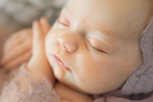 A sleeping baby rests peacefully with closed eyes and soft, glowing skin in natural light.