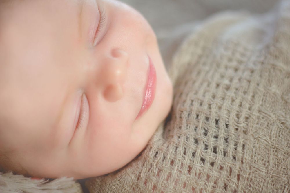 Peaceful newborn portrait series showing gentle sleeping expressions on textured fabric.