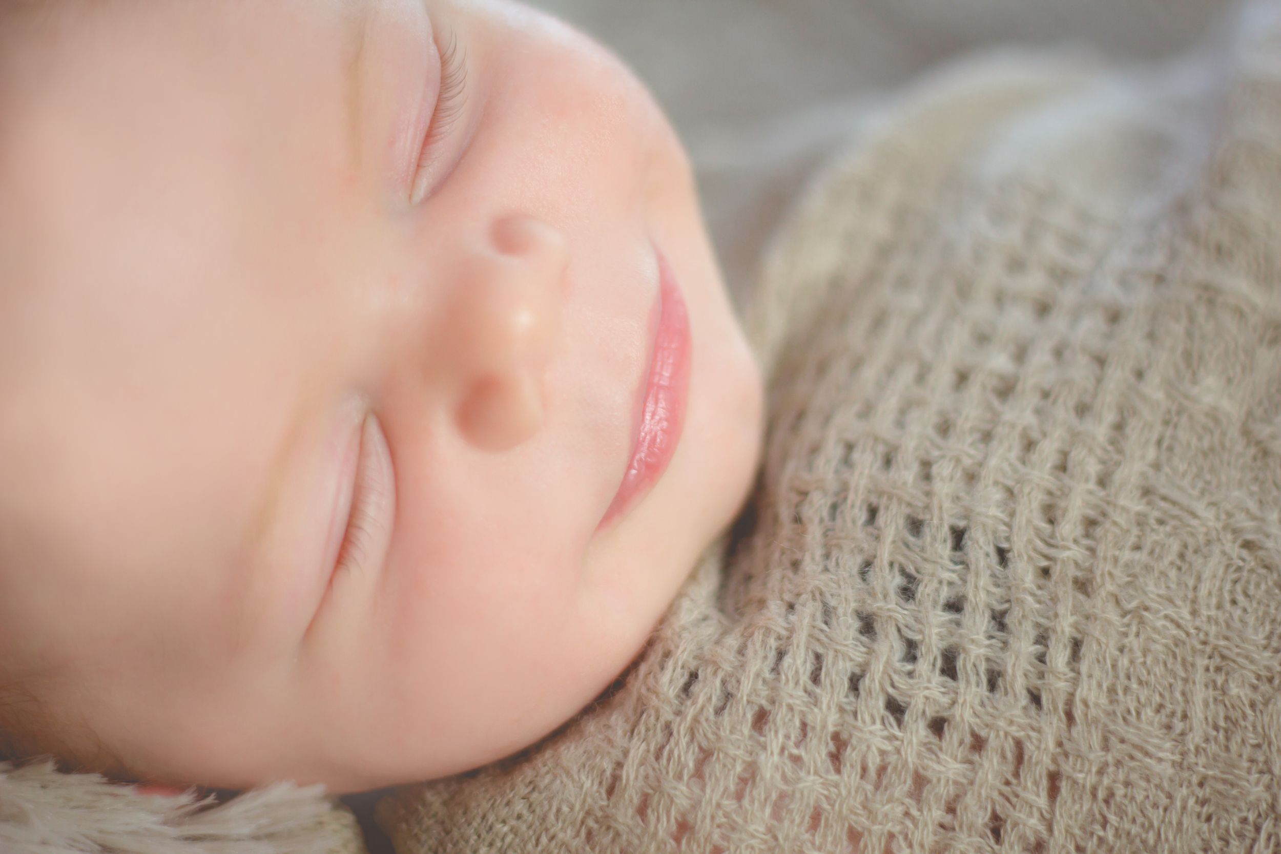Peaceful newborn portrait series showing gentle sleeping expressions on textured fabric.