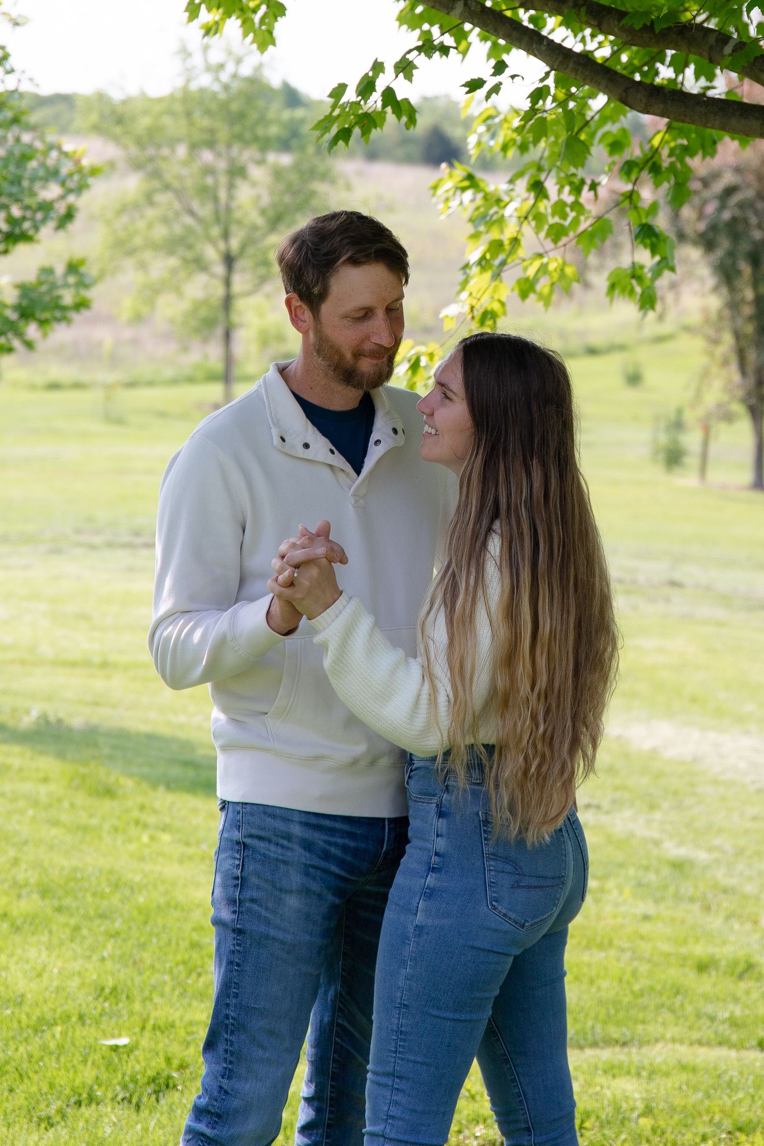 Romantic couple dancing together in a sunny meadow under green trees.  Couples photo session. Engagement photo session