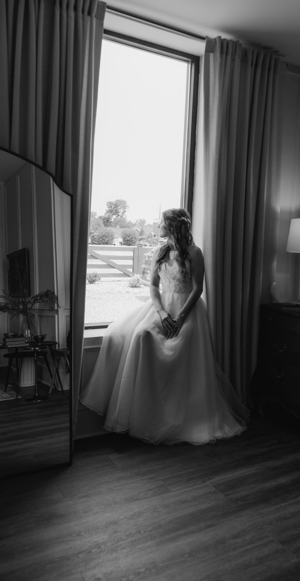 Artistic black and white photo of wedding dress silhouette against window light.