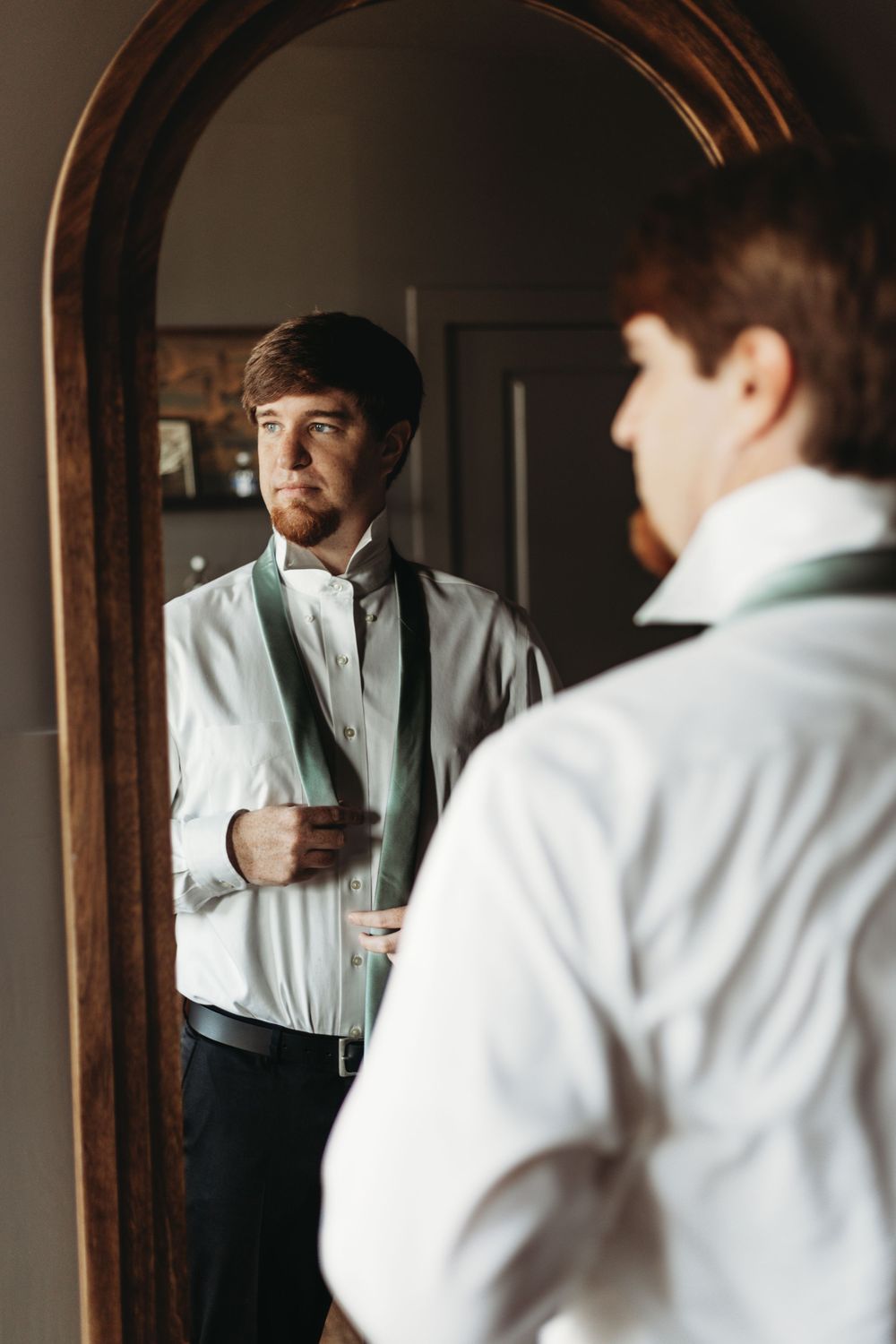 Getting ready scene with formal attire and mirror reflections in dark wood framed setting.