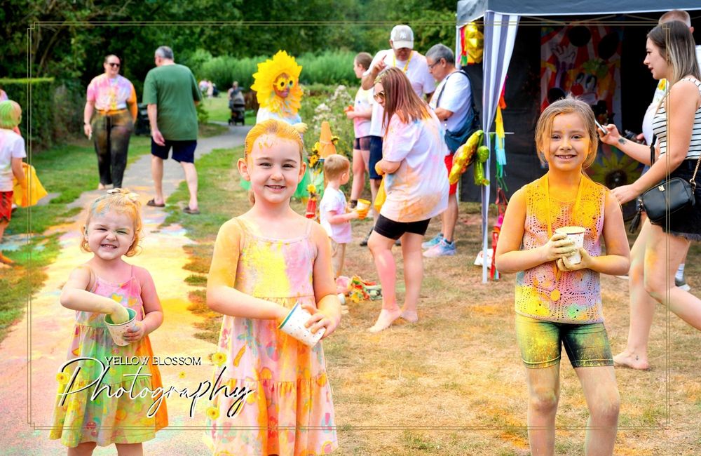 Participants covered in bright powder enjoy festivities at summer outdoor event.
