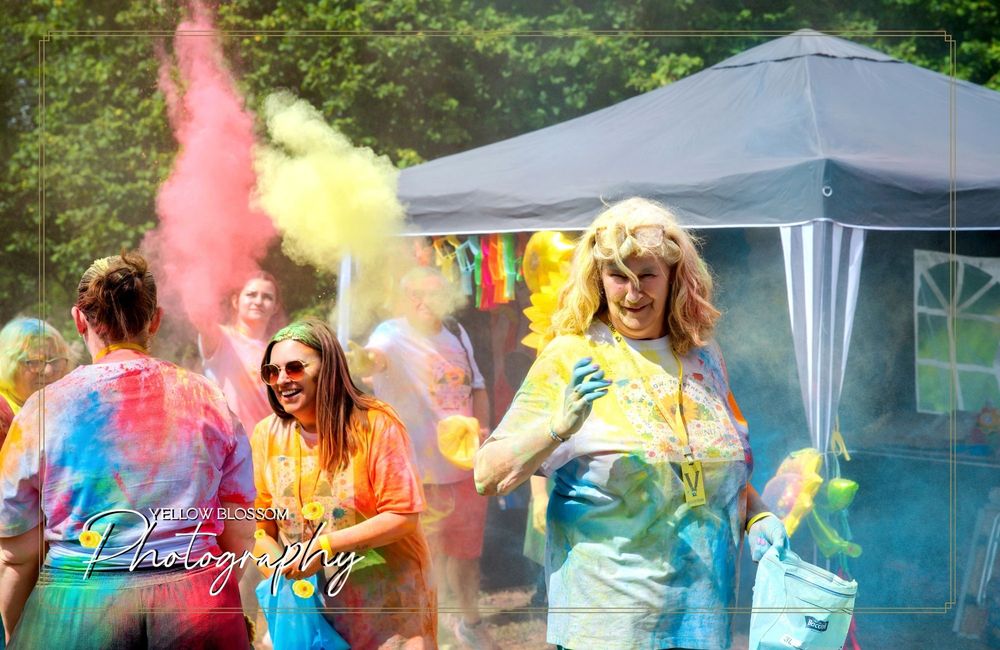 Pink and yellow powder clouds burst during an outdoor color festival celebration.