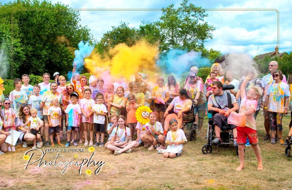 Crowd celebrating with multiple colored powder clouds exploding in an outdoor setting.