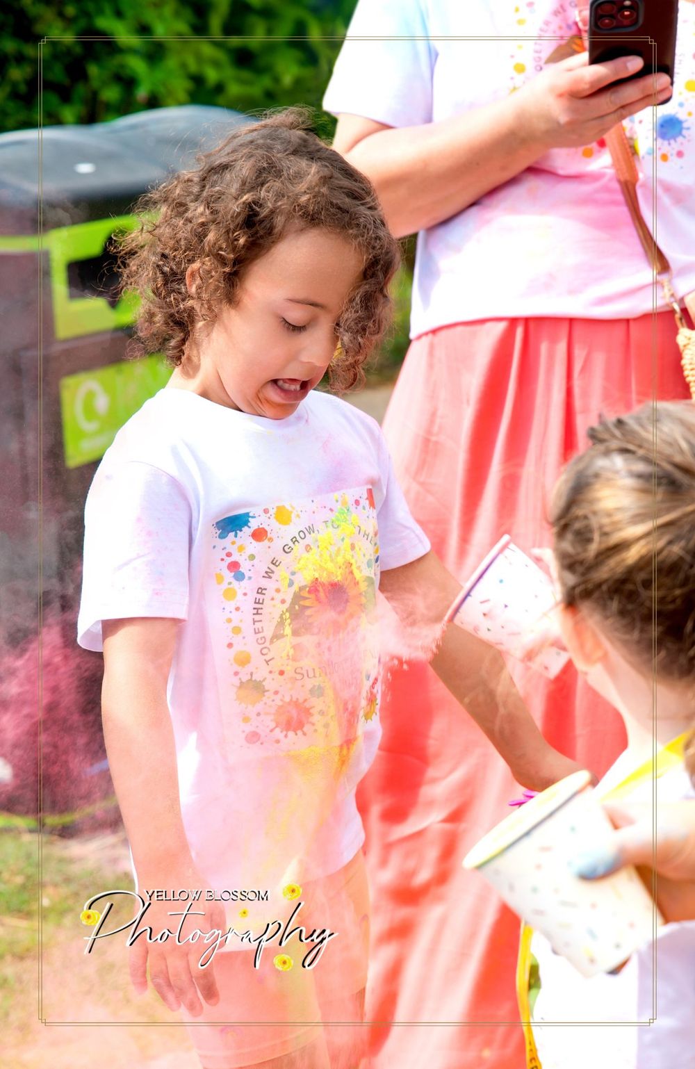 A joyful color run participant covered in bright powder during an outdoor festival celebration.