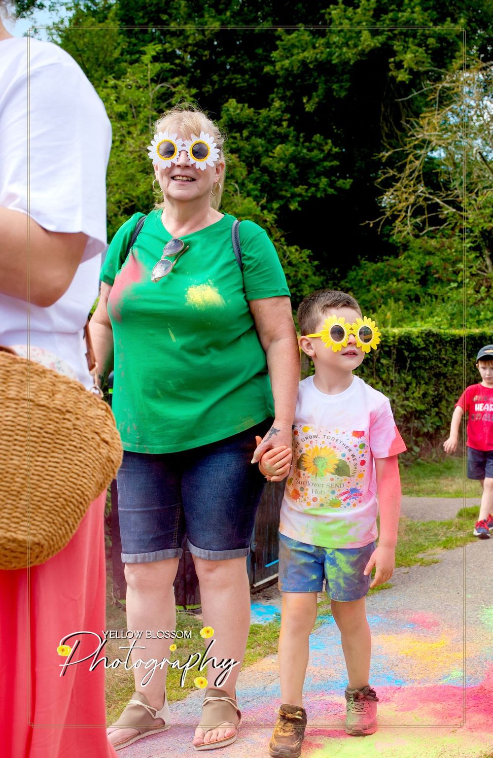 Participants in a color run event wearing colorful paint-splattered clothing and fun accessories outdoors.