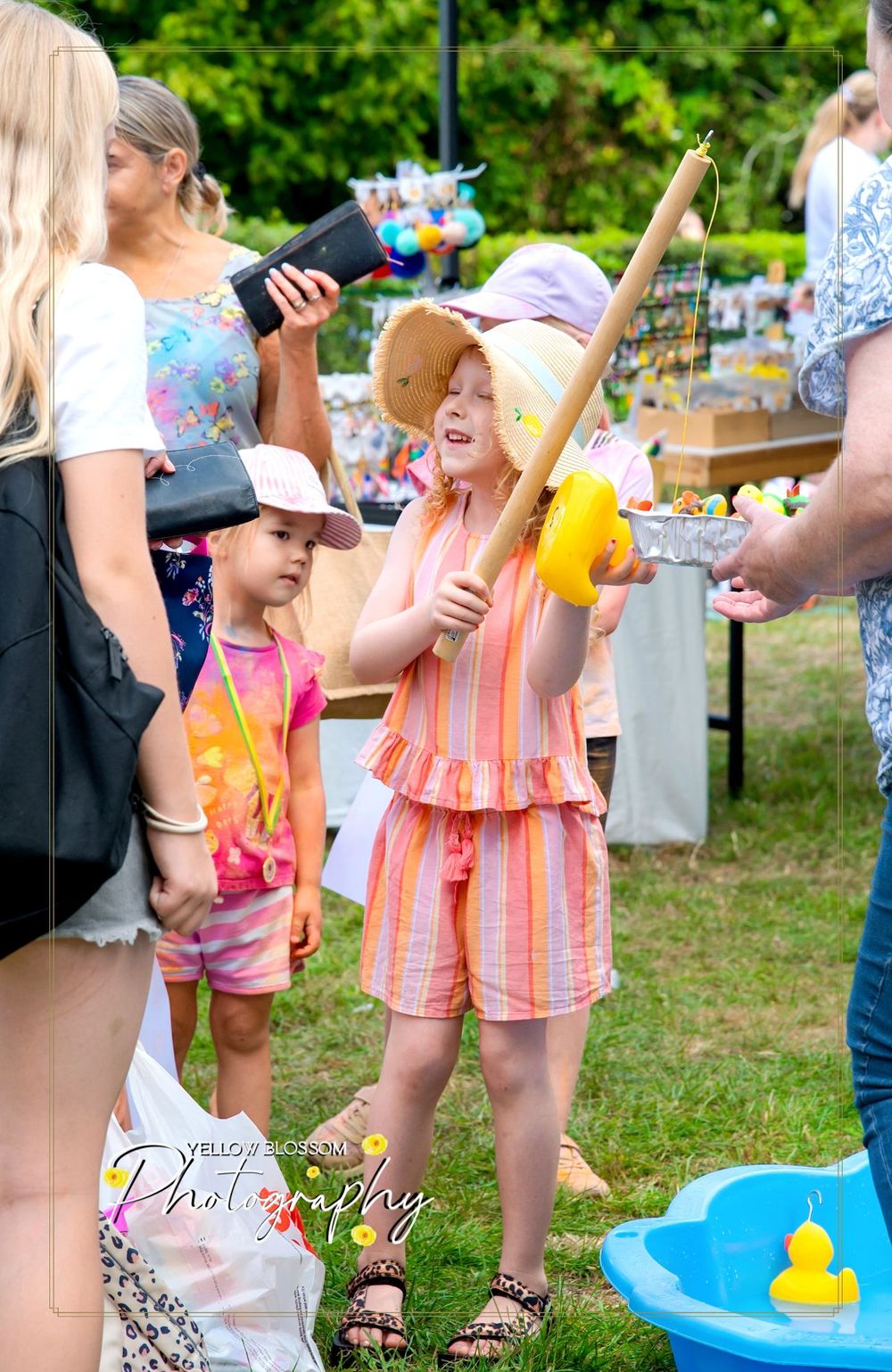 Children play with colorful play accessories and inflatable toys at an outdoor summer party.