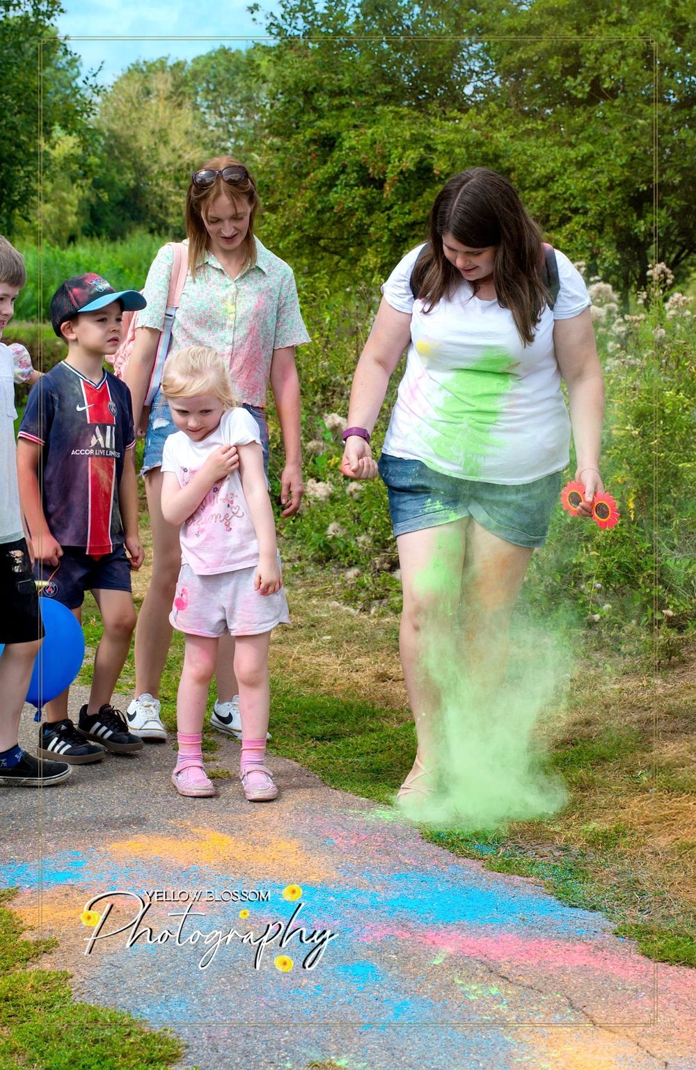 Colored powder explosion effect creates a vibrant display on a paved pathway during an outdoor event.