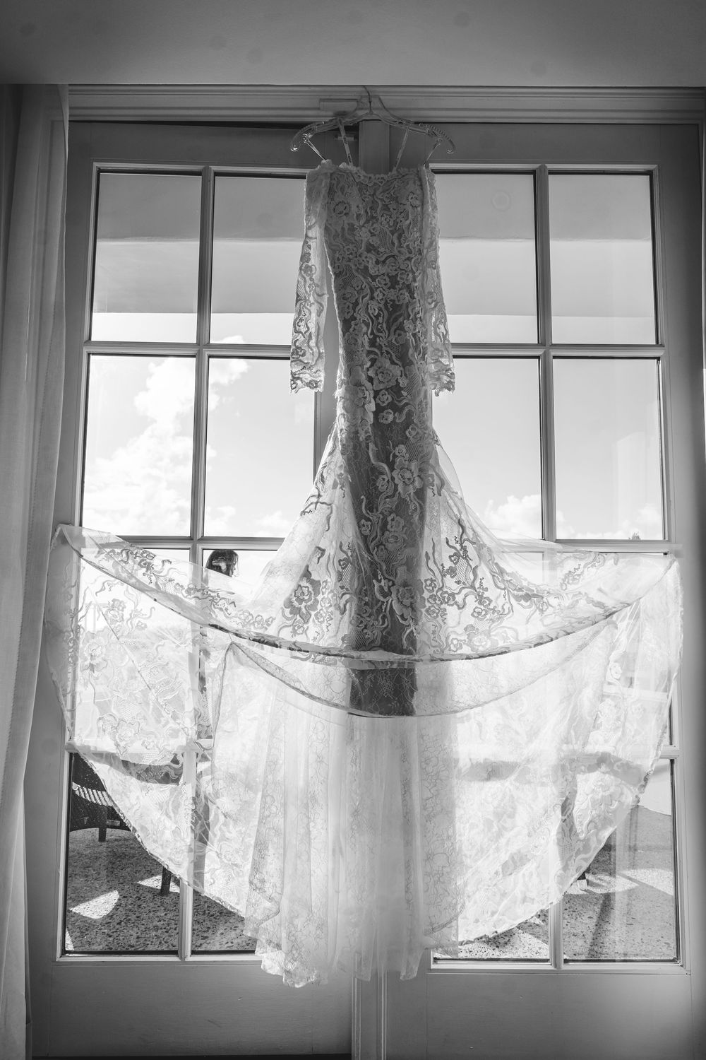 Multiple white sheer curtains hanging in front of windows in black and white.