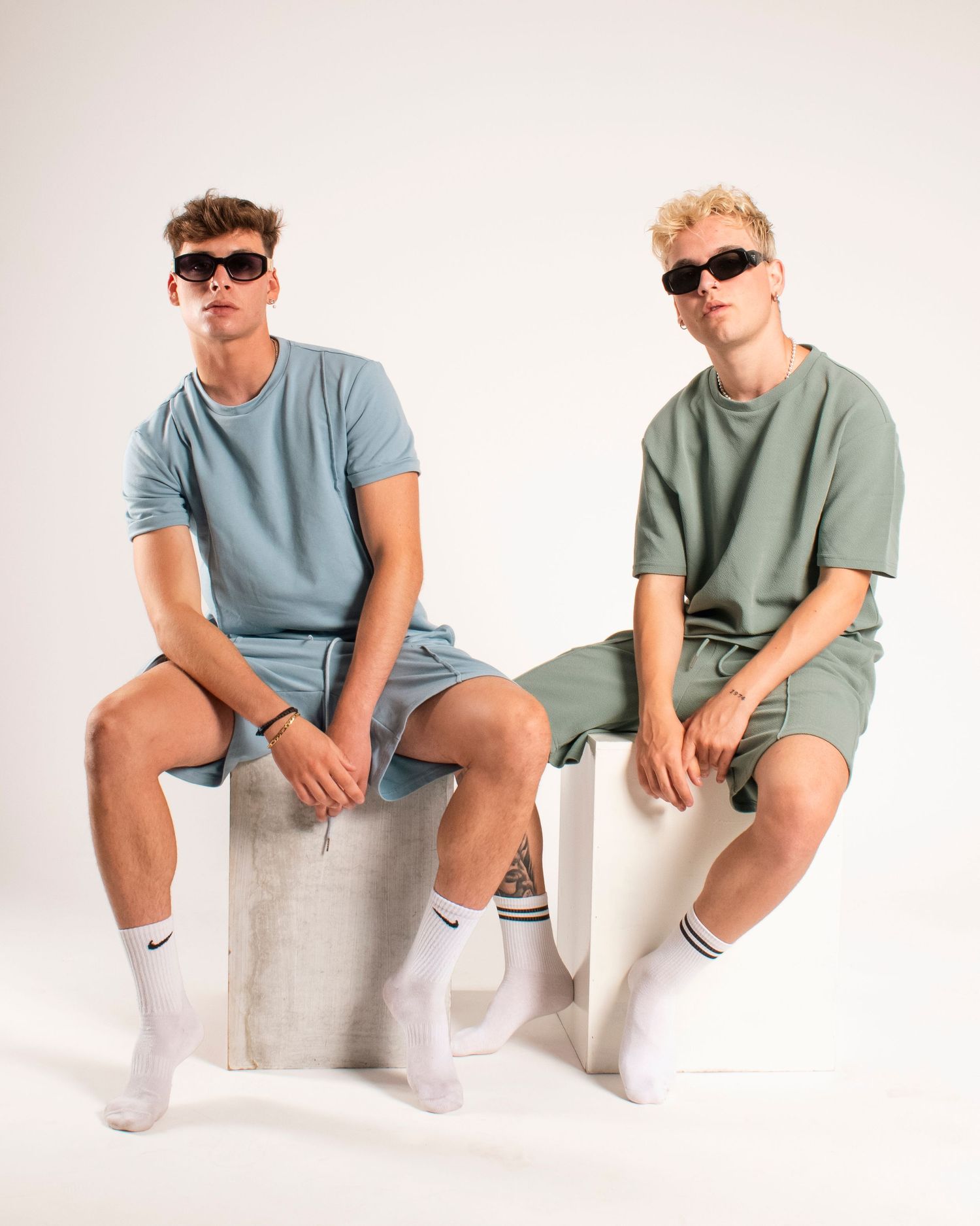 Fashion models wearing coordinated monochrome sets and white socks pose on geometric blocks.
