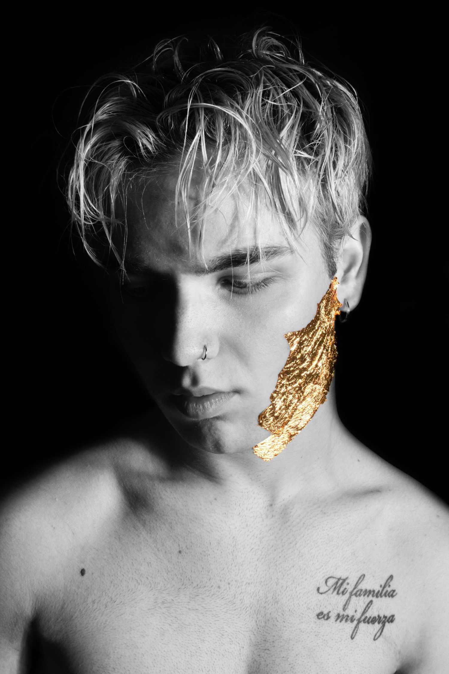 Moody black and white headshot with gold leaf accent and tousled hair.
