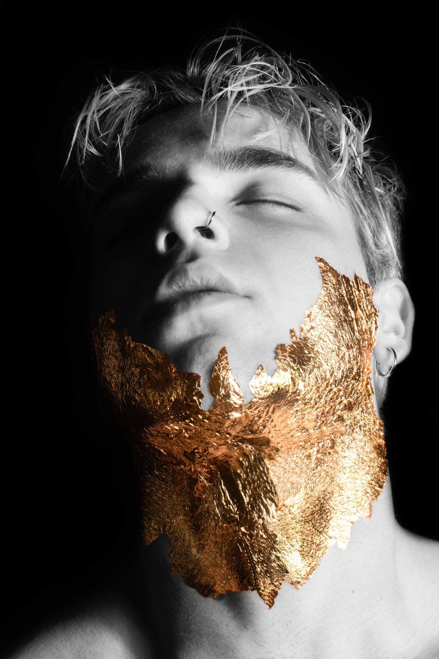 Artistic portrait with gold leaf beard effect on black and white background.