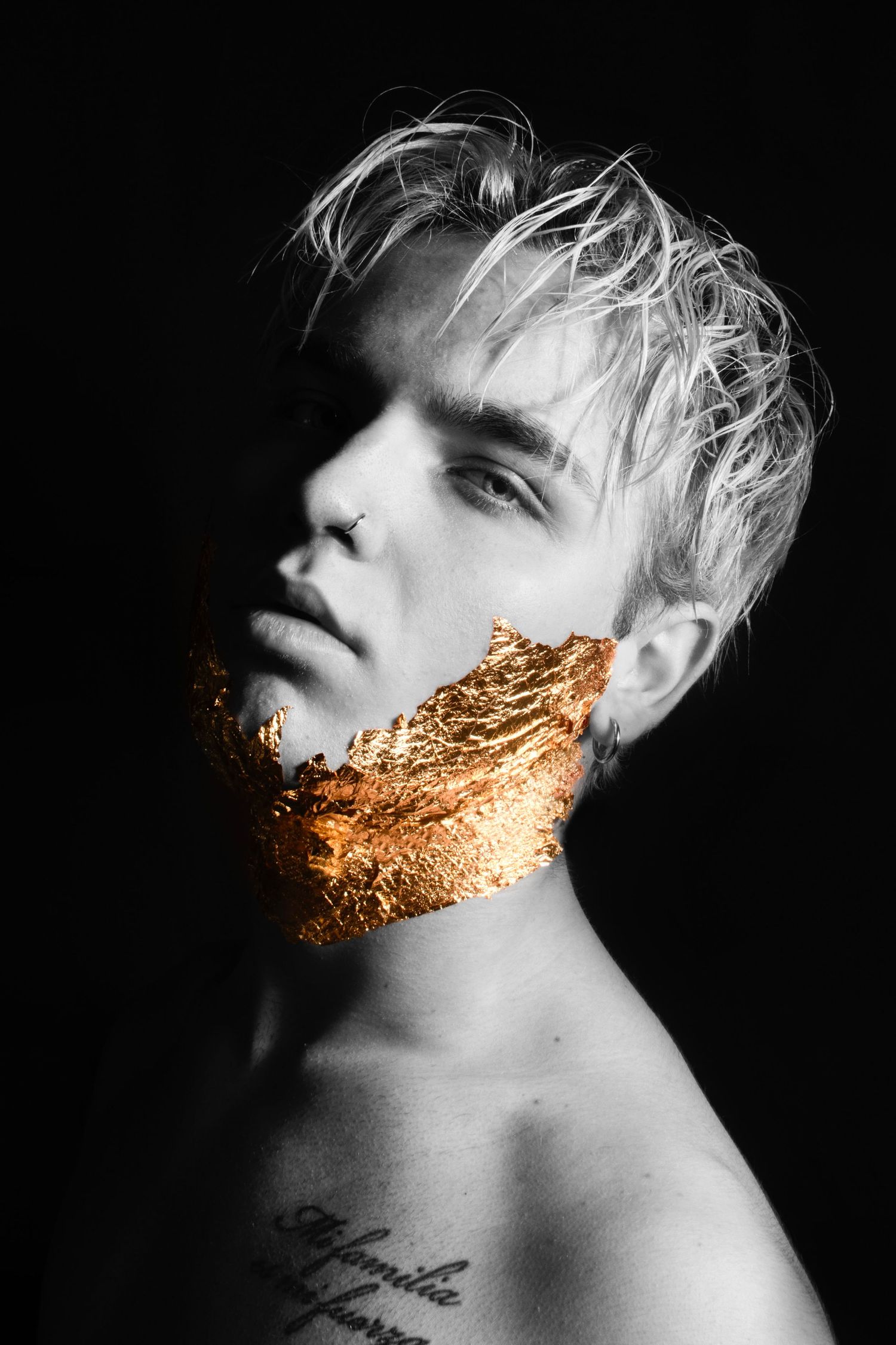 Minimalist portrait featuring gold leaf beard application against dark backdrop.
