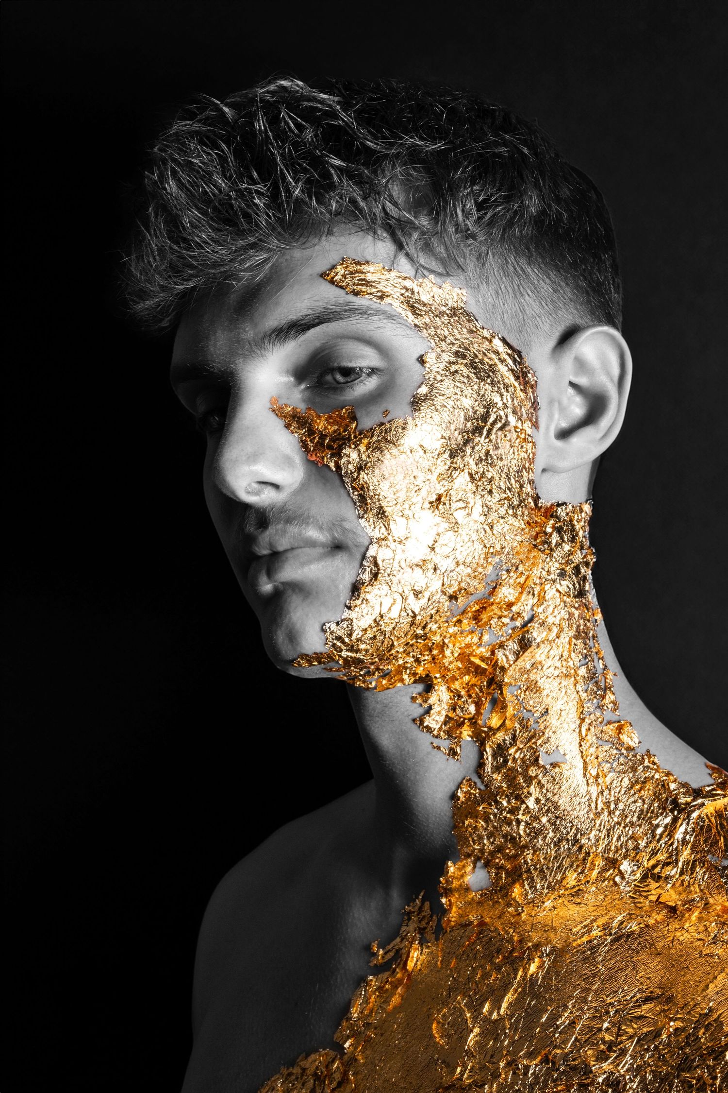 Dramatic portrait combining black and white photography with gold leaf texture on facial features.