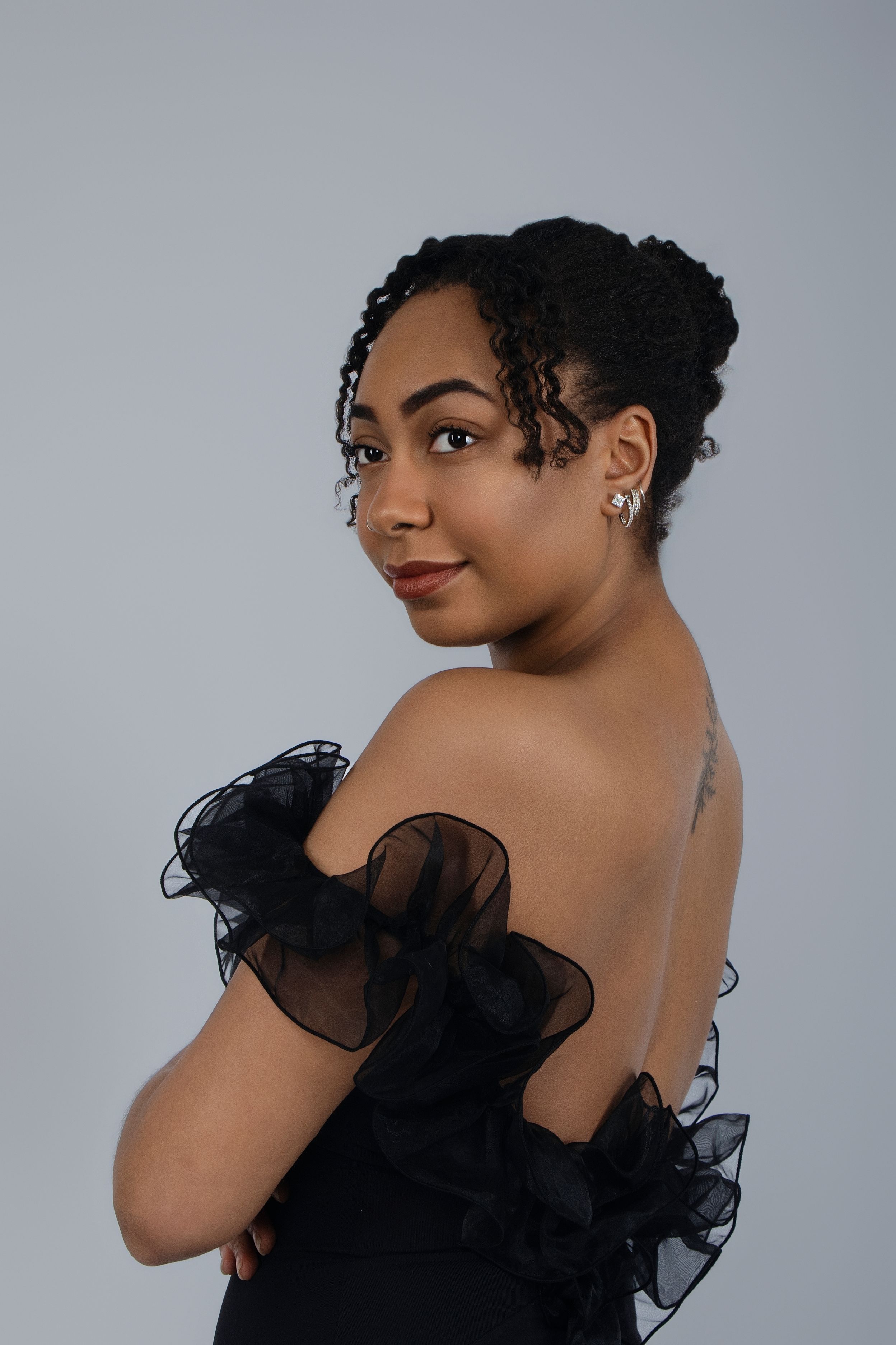 Elegant portrait series featuring black ruffled dress against grey studio background.