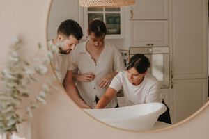 Three medical professionals in white uniforms examine something together in a bright, modern medical setting.