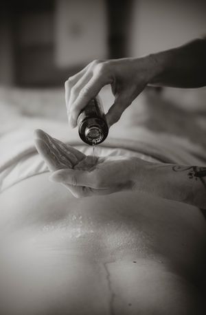 Black and white photo of hands pouring liquid medicine or essential oil from a small bottle into a palm.