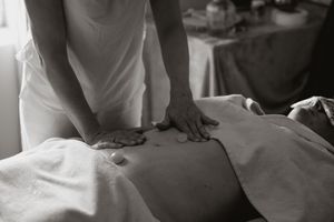 A black and white photo shows hands holding a white sheet, creating abstract folds and textures in the fabric.