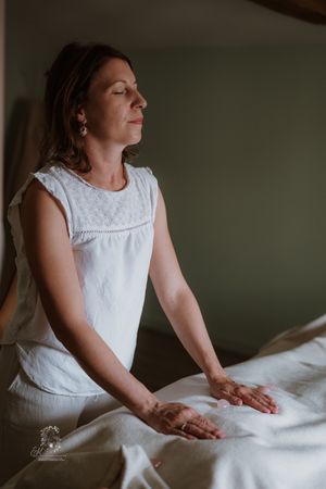 A series of soft, moody photos showing someone in a white sleeveless dress sitting against a dark background.