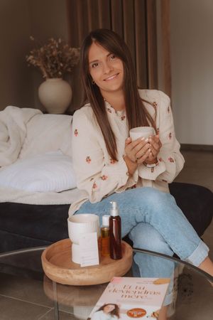 A cozy scene shows someone relaxing with a hot beverage and tissue box on a wooden tray while wearing light blue jeans.
