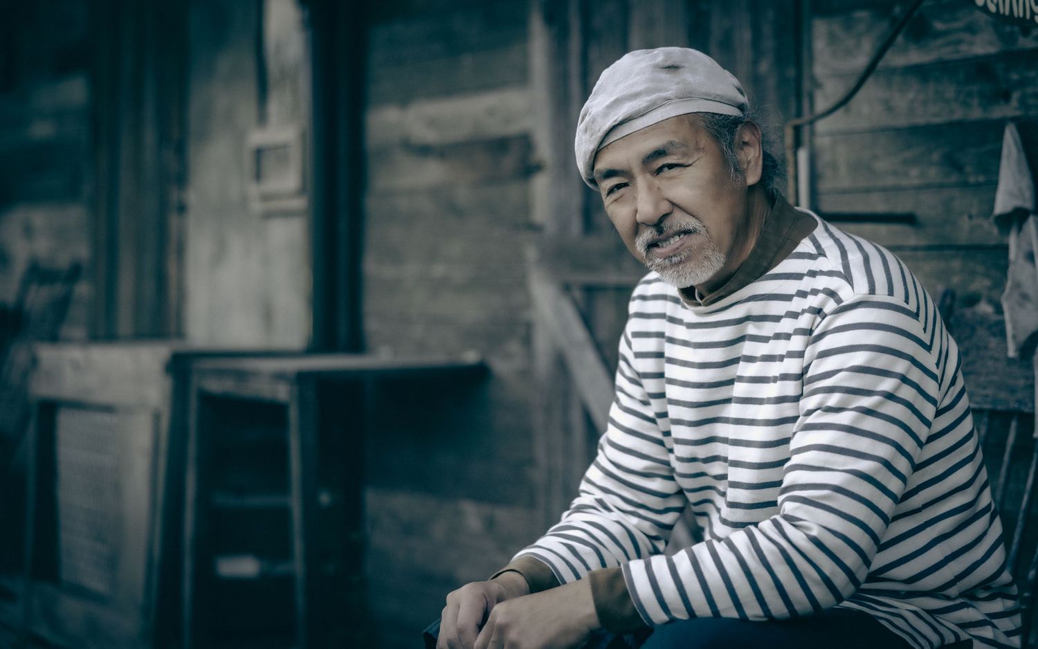 Vintage-toned portrait of person in striped sailor shirt against industrial background.