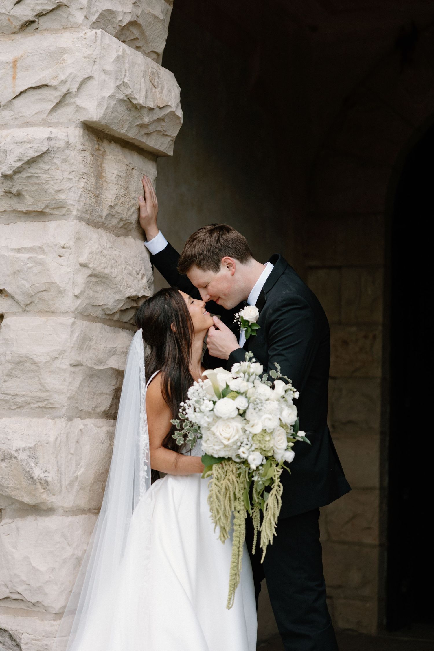 A romantic outdoor autumn wedding ceremony set under golden trees with the couple sharing a kiss in front of gathered guests.