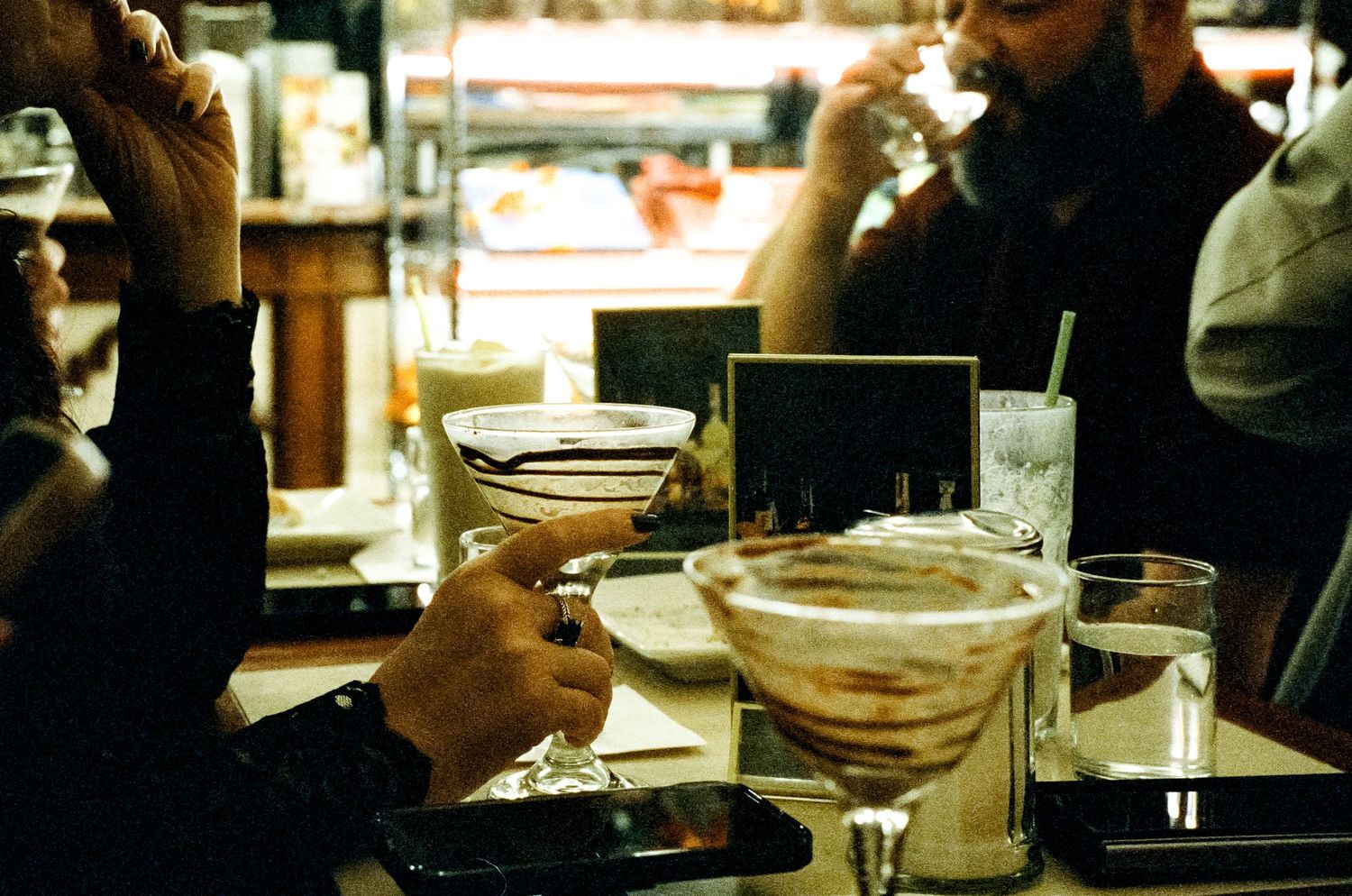 Martini glasses and cocktails on a dimly lit restaurant table.