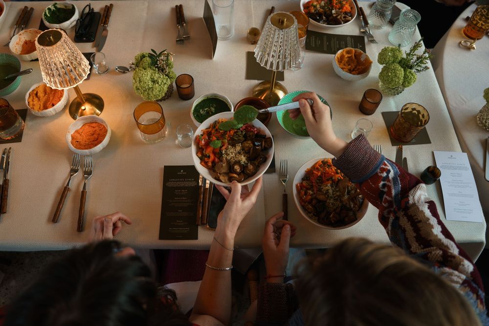 Overhead view of a dinner party table with colorful dishes being shared among guests by candlelight.