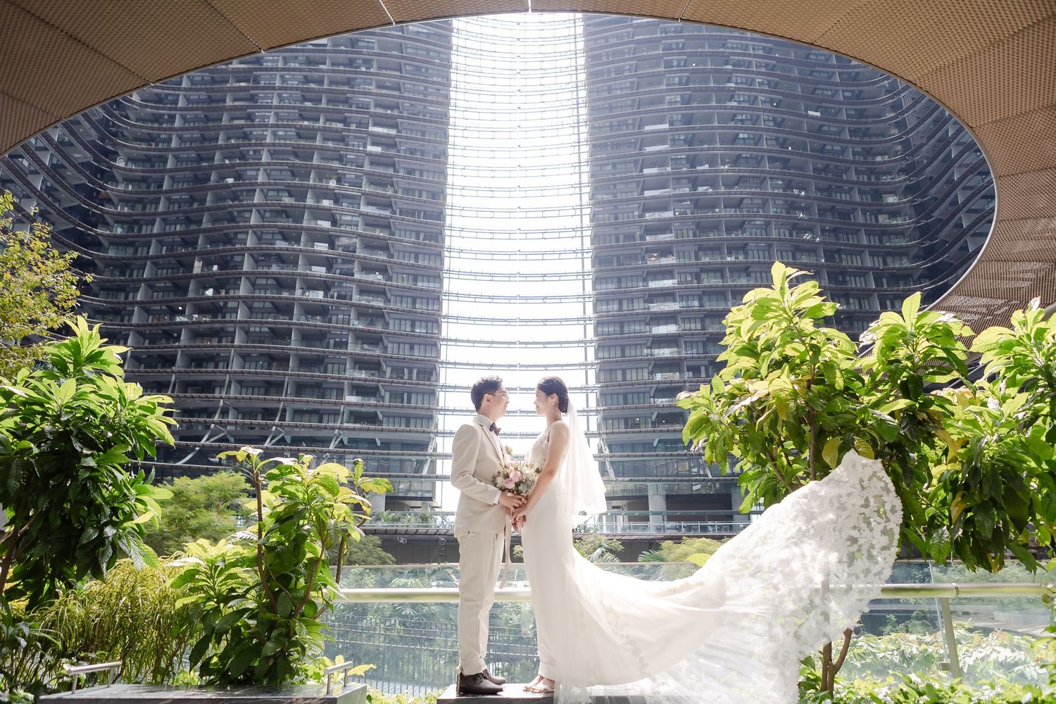 wedding couple in singapore's Marina One. White flowy dress and veil with beautiful architectural structure and foliage