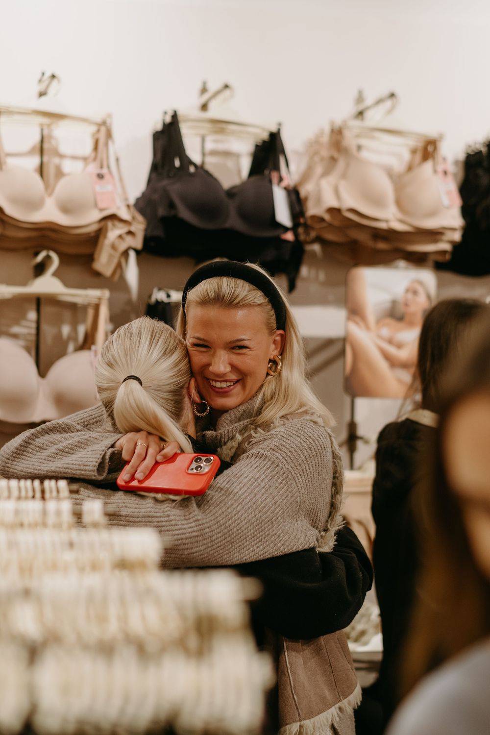 two women hugging each other at a clothing store while being captured by brand photographer for PR retail event in Stockholm