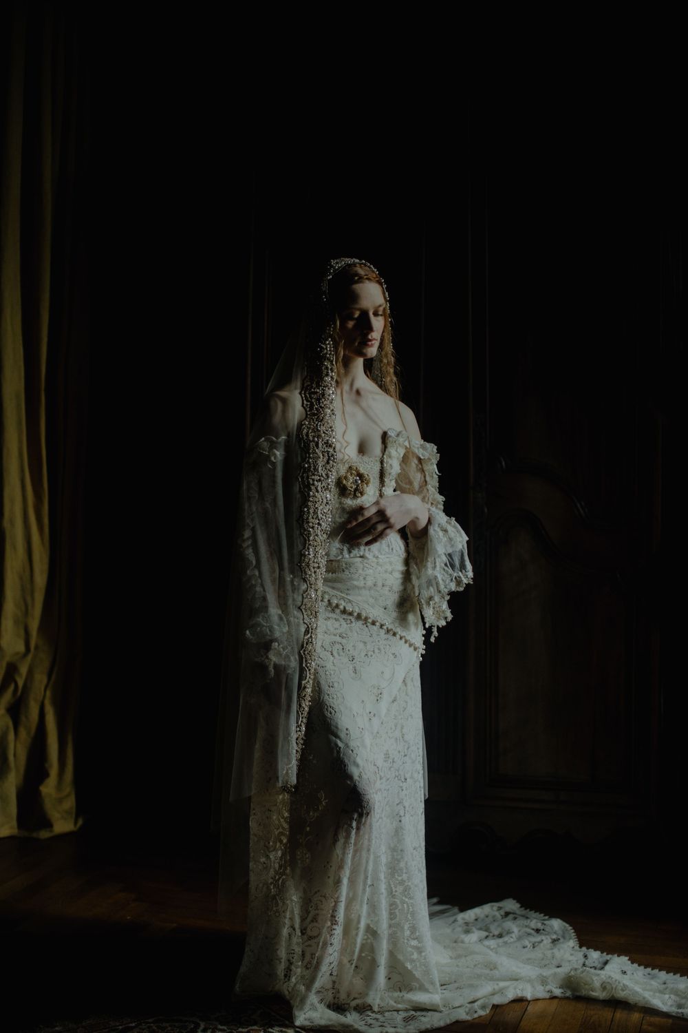 A vintage-inspired bridal portrait featuring an intricate lace wedding gown in dim lighting captured by a destination elopement photographer